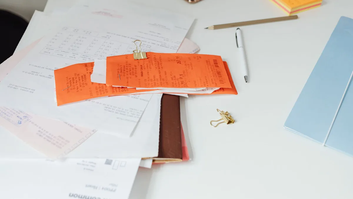 Desk seen from above with receipts, paper documents and office supplies laid out side by side