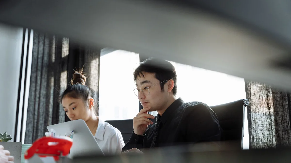 Two colleagues working with focus at their laptops in an office